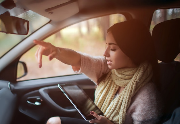 Mujeres que usan GPS en la computadora de la tableta para navegar en automóvil en vacaciones