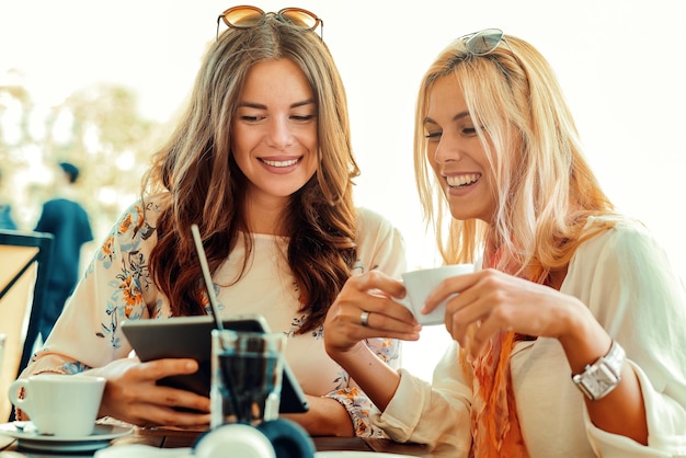 Mujeres que usan una tableta digital en el café