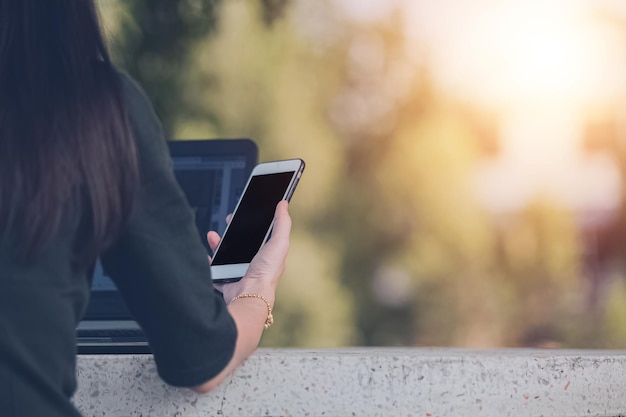 Mujeres que usan teléfonos inteligentes sentados en la mesa al aire libre en línea internet