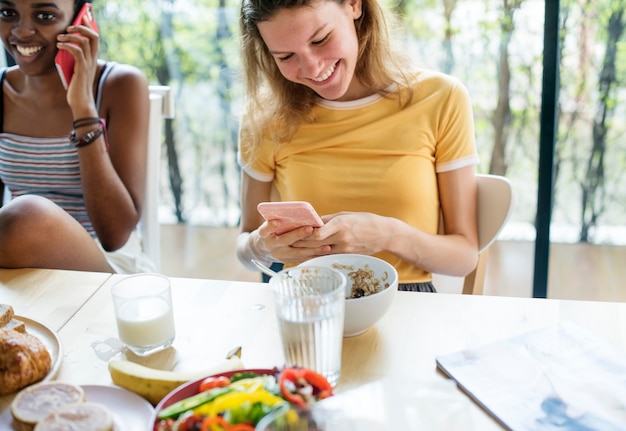 Mujeres que usan teléfonos móviles durante el desayuno.