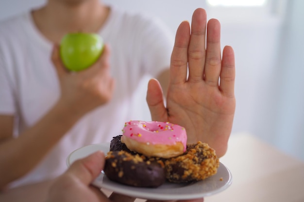 Las mujeres rechazan la comida chatarra o los alimentos poco saludables como las donas y eligen alimentos saludables como las manzanas verdes y las ensaladas Concepto de ayuno y buena salud