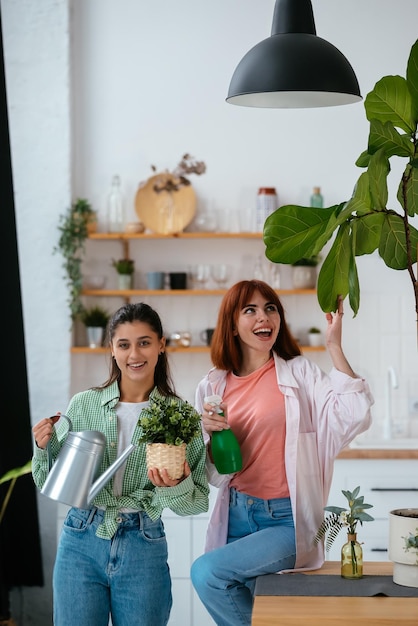 Foto mujeres con una regadera y una planta de interior.