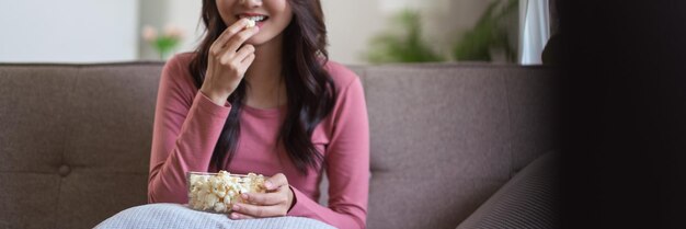 Las mujeres se relajan en el sofá para comer palomitas de maíz y ver películas en la televisión mientras disfrutan del estilo de vida en casa