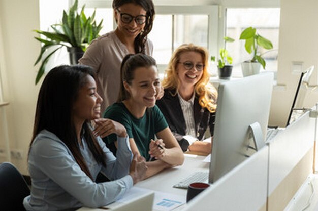 mujeres en una reunión uno de ellos está sonriendo y el otro es una mujer delante de una pantalla de computadora tha