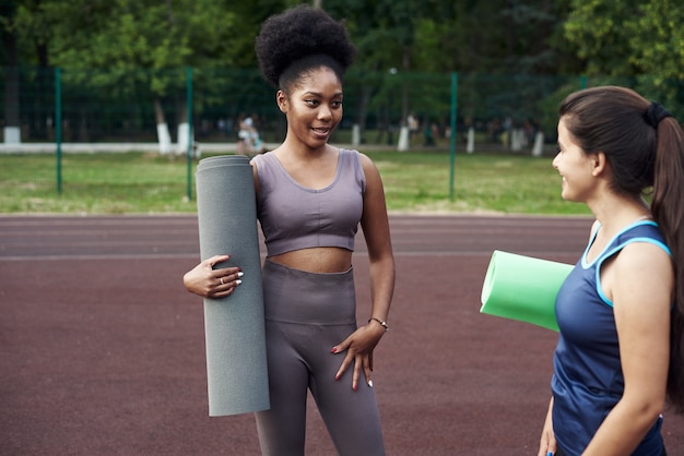 Mujeres en ropa deportiva con colchoneta de fitness