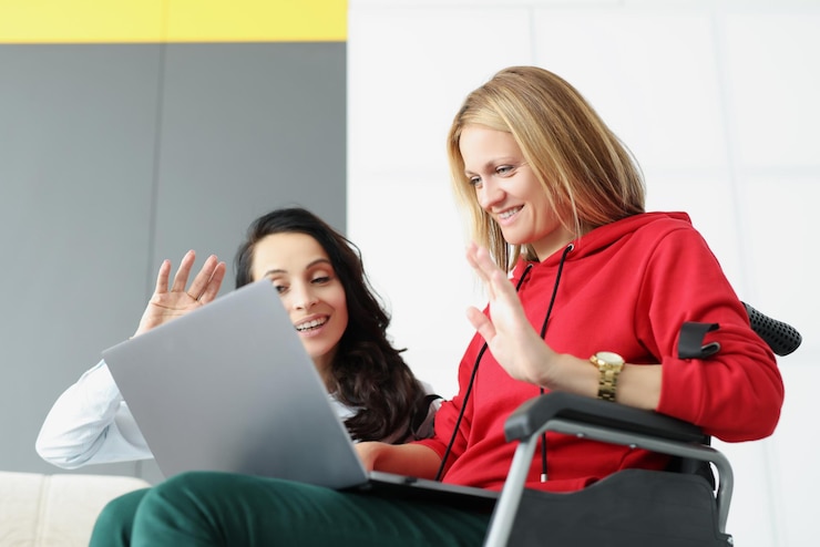 Foto mujeres saludando a la familia a través de una videollamada en línea usando una computadora portátil mujer visita a un amigo en silla de ruedas