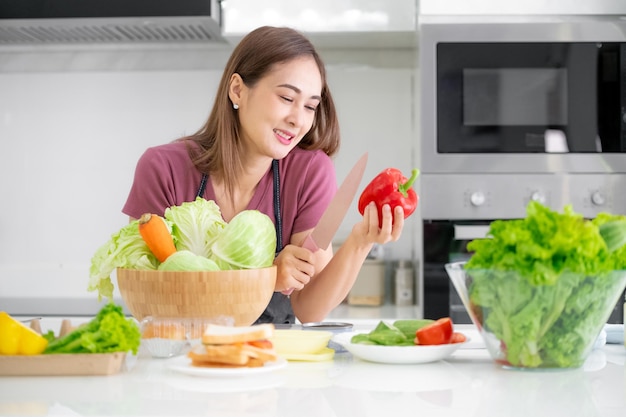 Las mujeres sanas que cocinan ensalada de verduras comen el desayuno