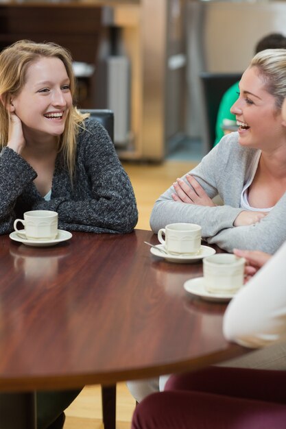 Mujeres sentadas en la cafetería riendo