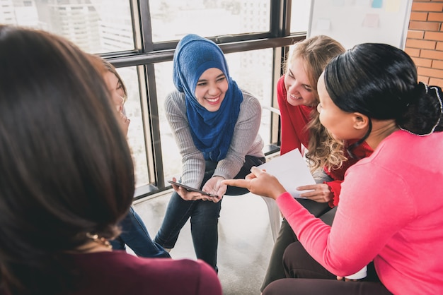 Mujeres sentadas en círculo disfrutando compartiendo historias en una reunión grupal