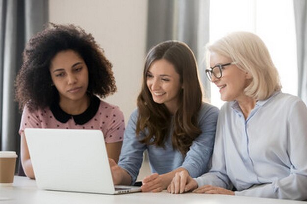 mujeres sentadas frente a una computadora portátil con una mujer mirando la pantalla