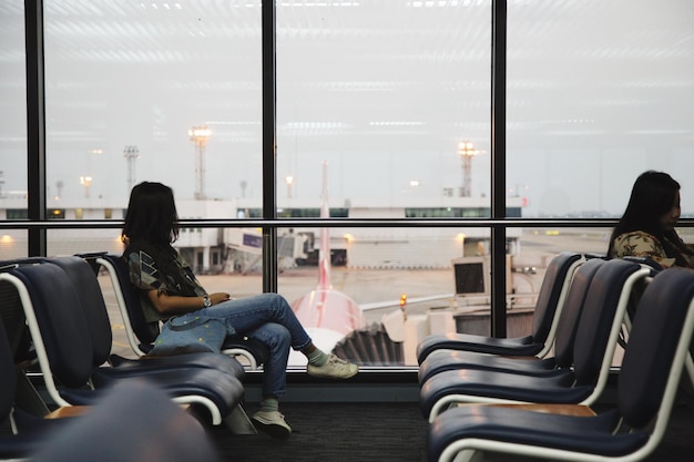 Mujeres sentadas en sillas en la zona de salida del aeropuerto