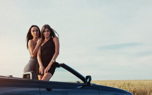 Mujeres sexy posando en un auto convertible negro
