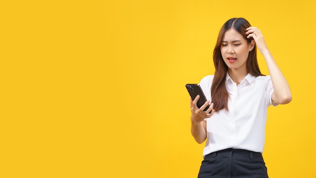 Las mujeres se sienten confundidas al leer datos en un teléfono inteligente con un espacio vacío en un fondo amarillo aislado