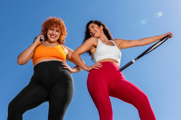 Mujeres sonrientes de ángulo bajo con raquetas