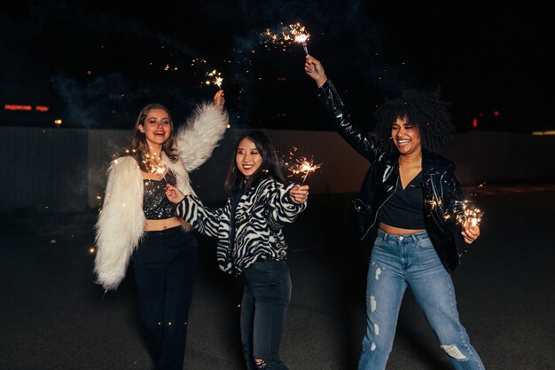 Foto mujeres sonrientes con chispas de fuego de pie al aire libre