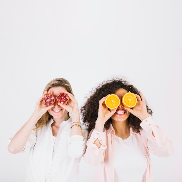 Foto mujeres sonrientes con granada y naranja