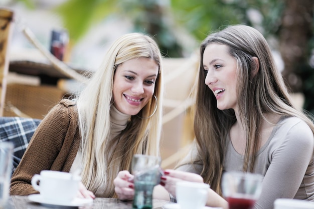 mujeres sonrientes muy lindas bebiendo un café sentadas dentro en un café restaurante