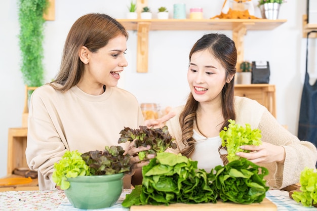 Mujeres sonrientes preparando verduras frescas y saludables para ensaladas mujer sentada en la despensa en una hermosa cocina interior La comida de dieta limpia de productos e ingredientes locales Mercado fresco