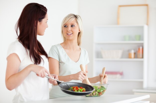 Mujeres sonrientes que cocinan la cena