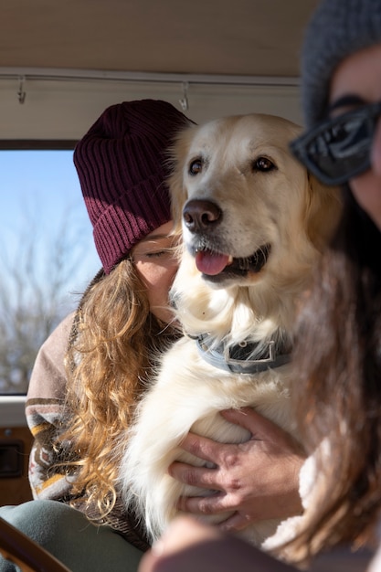 Mujeres sosteniendo a su labrador mientras van de viaje de invierno en su autocaravana