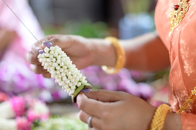 Las mujeres tailandesas en traje tradicional tailandés están decorando flores.