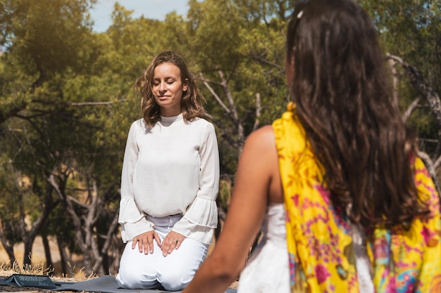 Mujeres en una terapia de atención plena en el bosque Meditación líder del entrenador feliz
