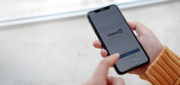 Las mujeres tienen un teléfono inteligente con la aplicación de linkedin en la pantalla