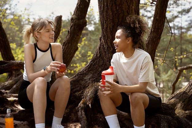 Mujeres de tiro completo con agua y manzana.