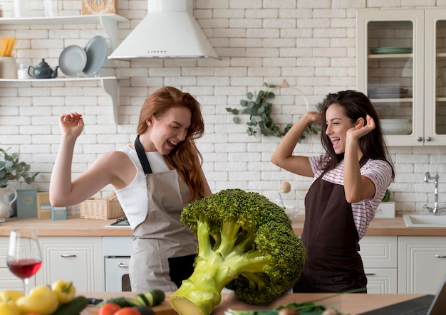 Mujeres de tiro medio con brócoli gigante.