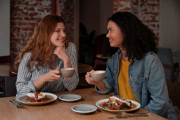 Mujeres de tiro medio en cafetería.