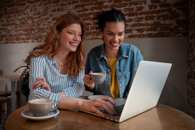 Mujeres de tiro medio con laptop en cafetería