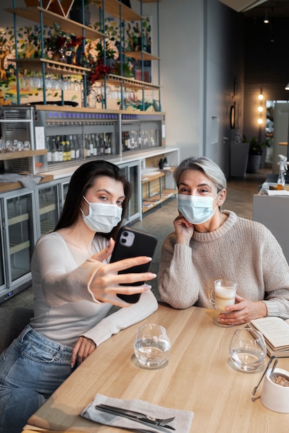 Mujeres de tiro medio tomando selfie en interiores