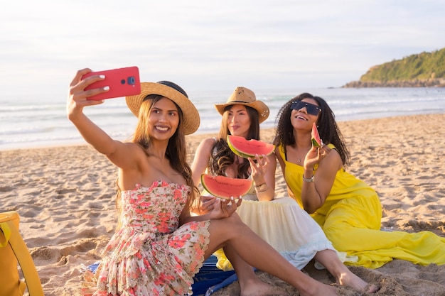 Mujeres tomándose una selfie durante un picnic en la playa durante el atardecer