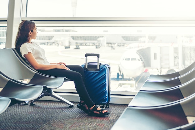 Mujeres turísticas que usan el teléfono en el aeropuerto internacional esperando el embarque.