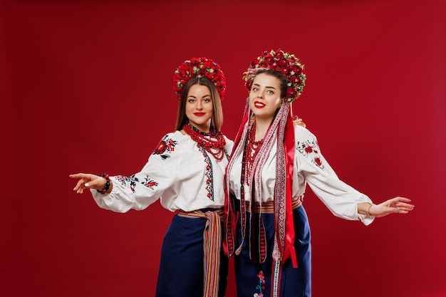 Mujeres ucranianas en ropa étnica tradicional y corona floral roja sobre fondo de estudio viva magenta Vestido nacional bordado llamada vyshyvanka Ore por Ucrania