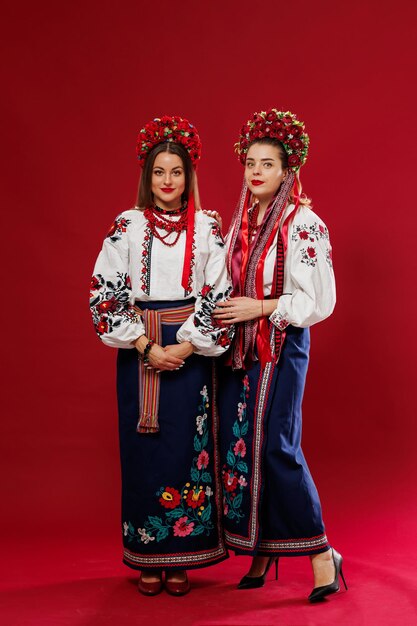 Mujeres ucranianas en ropa étnica tradicional y corona floral roja sobre fondo de estudio viva magenta Vestido nacional bordado llamada vyshyvanka Ore por Ucrania
