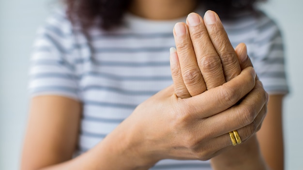 Las mujeres usan la mano para sostener la palma y los dedos con sensación de dolor, sufrimiento, dolor y hormigueo. Concepto de síndrome de Guillain barre y enfermedad de manos entumecidas.