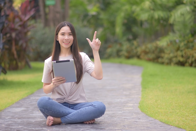 Las mujeres usan tabletas compras en línea sentado parque de la ciudad