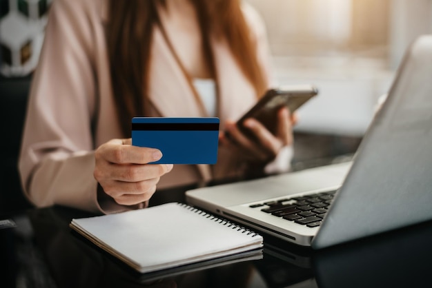 Las mujeres usan tarjetas de crédito para realizar transacciones financieras a través de teléfonos, tabletas y computadoras portátiles por la mañana.