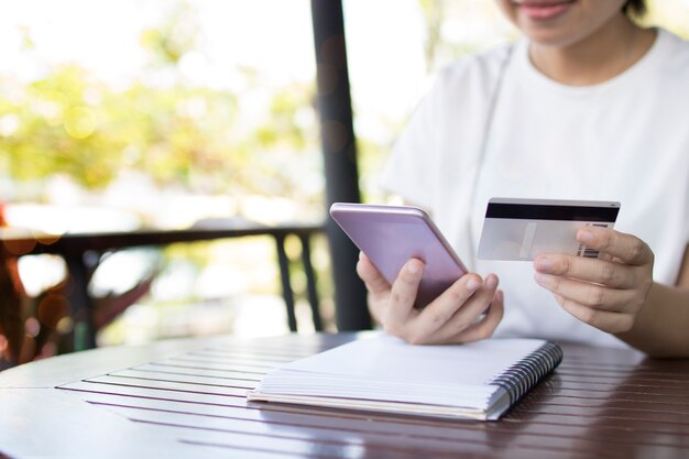 Las mujeres usan el teléfono para la banca móvil con tarjeta de crédito para comprar en línea