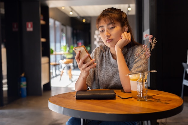 Las mujeres usan el teléfono inteligente en la cafetería