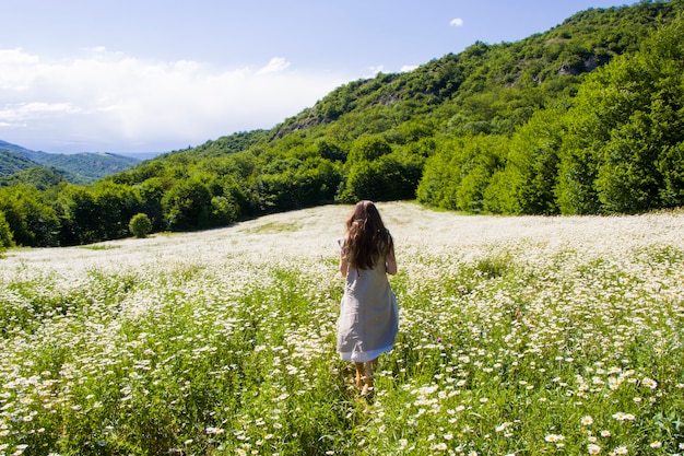 Mujeres con vestido en campo de flores de margarita durante la luz del sol