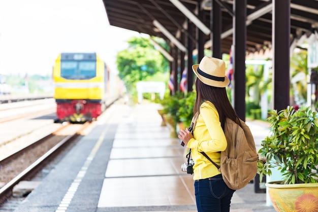 Las mujeres del viajero caminando solo El equipaje que lleva y espera el tren en la estación de ferrocarril