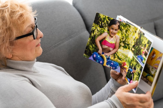 Mujeres viendo álbum familiar en casa, anciana viendo fotolibro