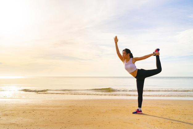 Mujeres yoga en la playa por la mañana con hermoso amanecer