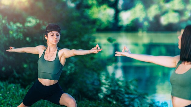 Mujeres de yoga por la pose del guerrero del lago