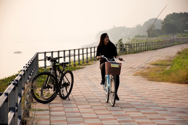 MUKDAHAN TAILANDIA 2 DE OCTUBRE Mujeres tailandesas en bicicleta en la calle a orillas del río Mekhong por la noche en la ciudad de Mukdahan el 2 de octubre de 2019 en Mukdahan Tailandia