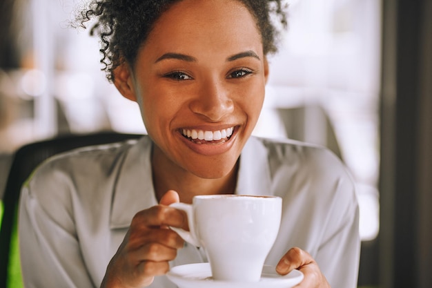 Mulata muito sorridente a tomar café e a sentir-se bem