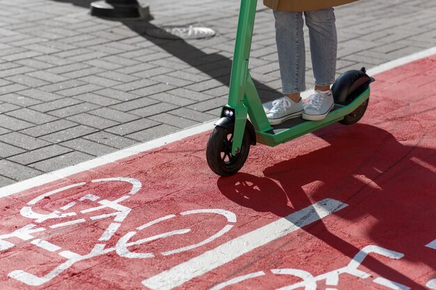 Mulher a andar de scooter ao longo da estrada da pista de bicicletas na cidade