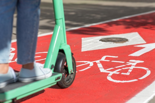 Mulher a andar de scooter ao longo da estrada da pista de bicicletas na cidade